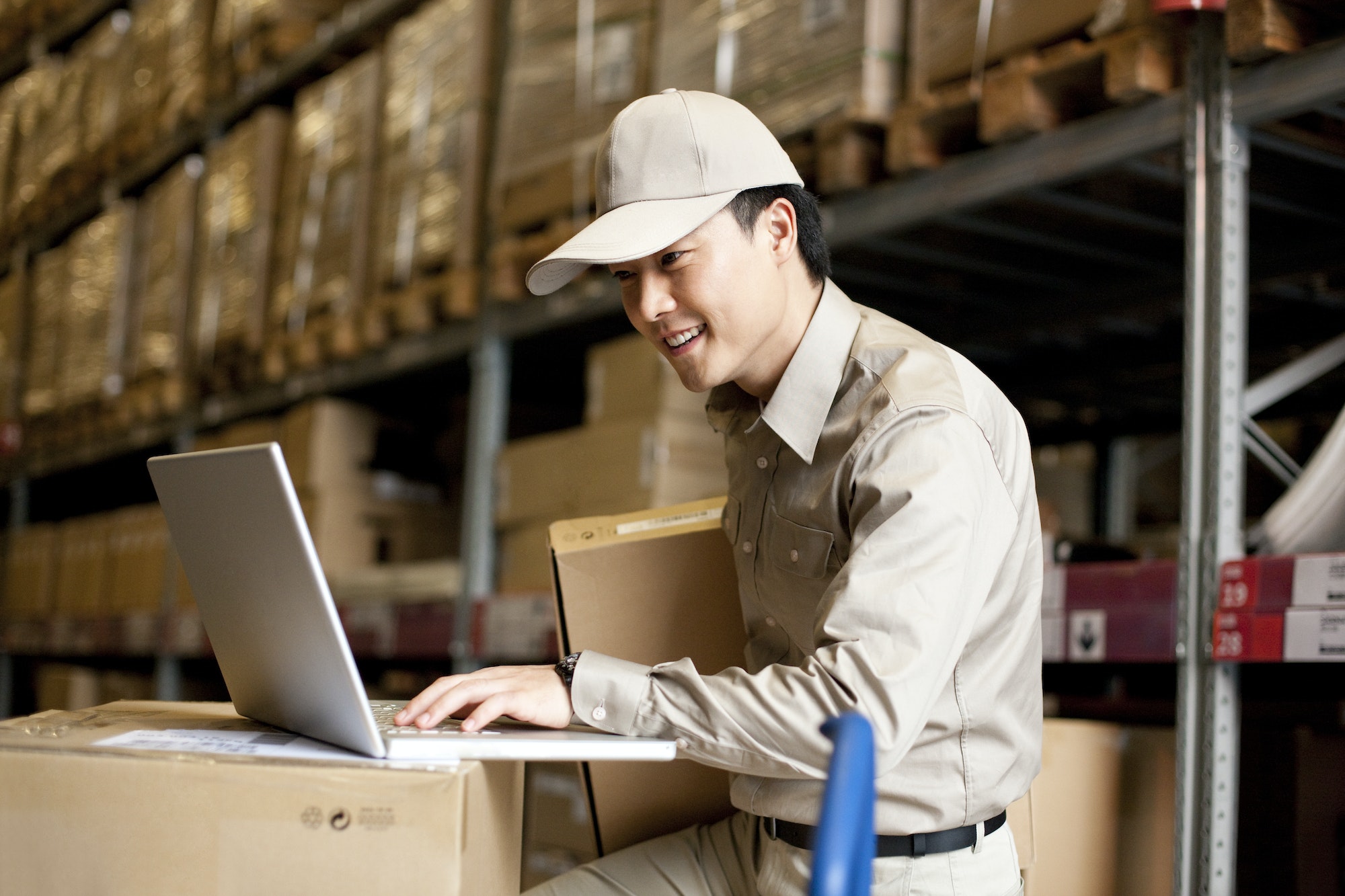 Male Chinese warehouse worker using a laptop